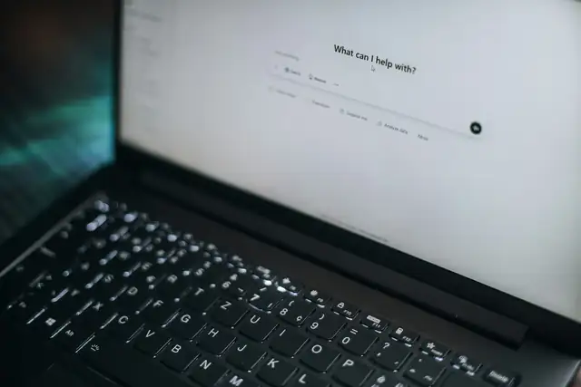Bærbar PC med en KI-assistent som spør «Hva kan jeg hjelpe med?»