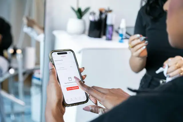 Hender som holder en mobil med en app for timebestilling